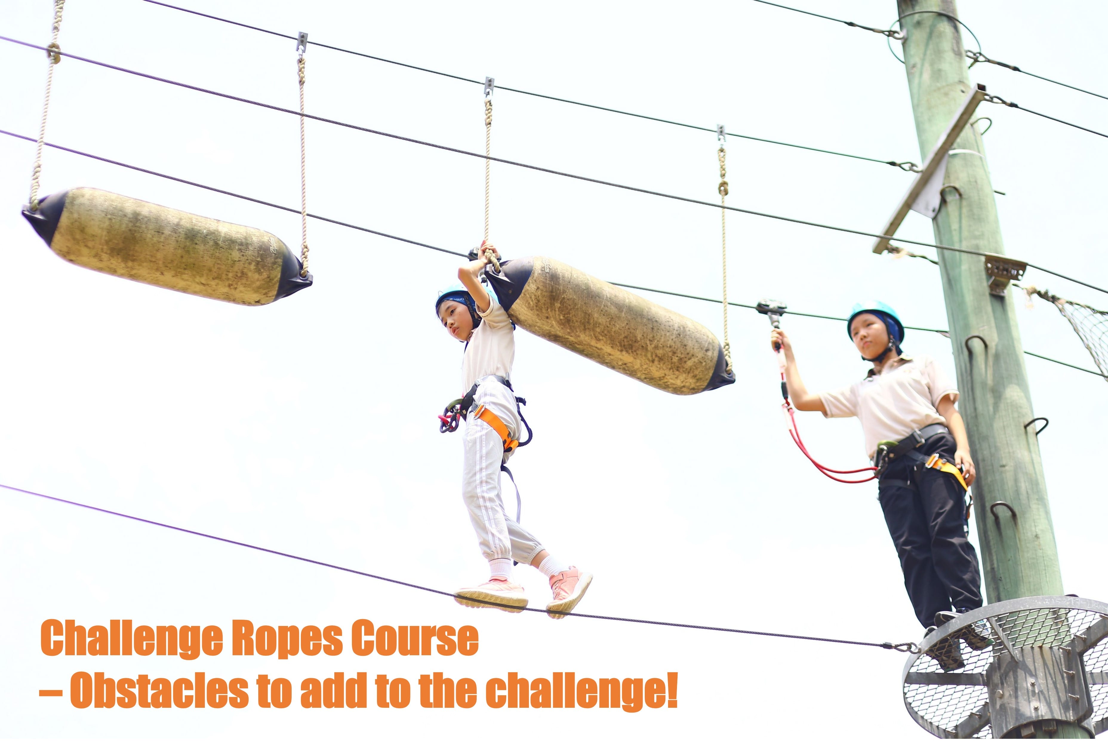 Two P5 students involved in the challenge ropes course going through obstacles